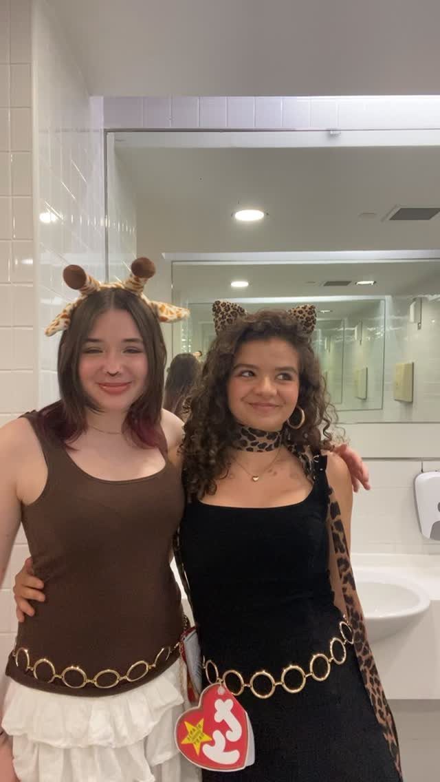 Two women in animal-themed costumes, one featuring a large red Beanie Baby tag.