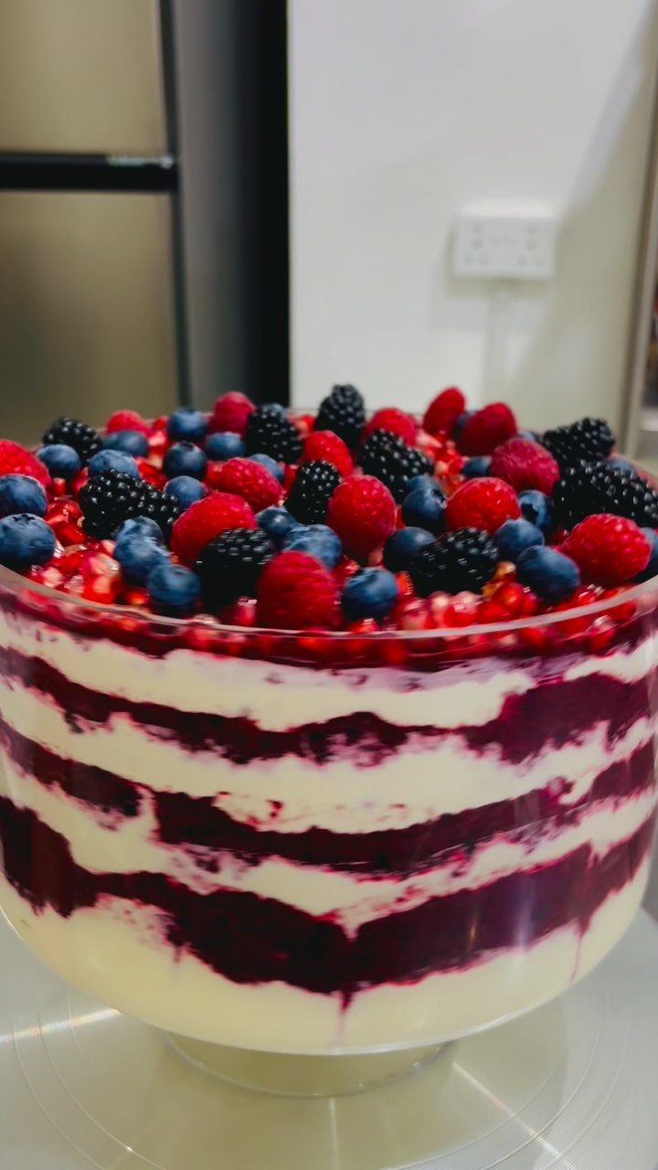 Berry trifle with alternating cream and purple layers topped with mixed fresh berries.