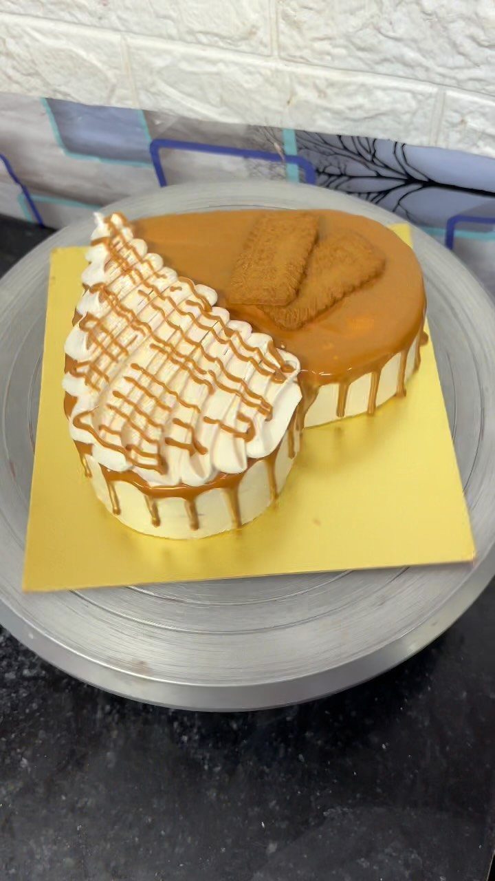 Biscoff cake with caramel glaze, lotus biscuits, and piped frosting on yellow base