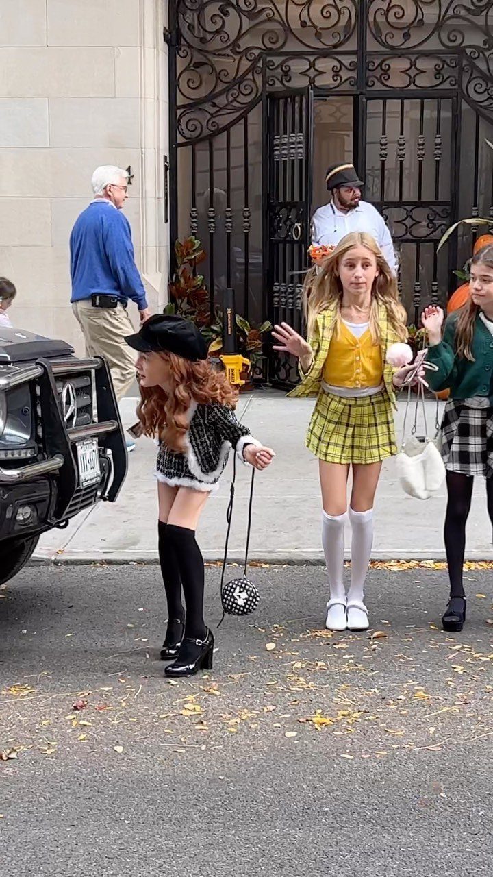 Two girls wearing yellow and black plaid Clueless costumes standing on a street.