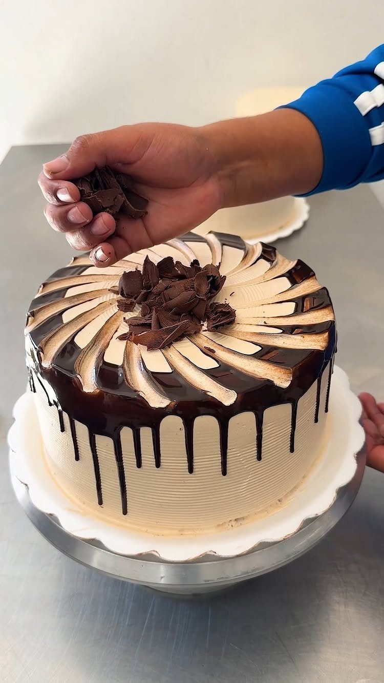 21 Cake Decoration Ideas for Every Skill Level 6 Chocolate shavings being sprinkled onto a decorated cake with chocolate ganache drip.