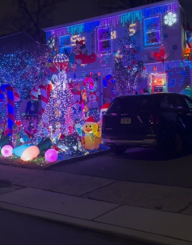 House and yard decorated with colorful Christmas lights and inflatables at night