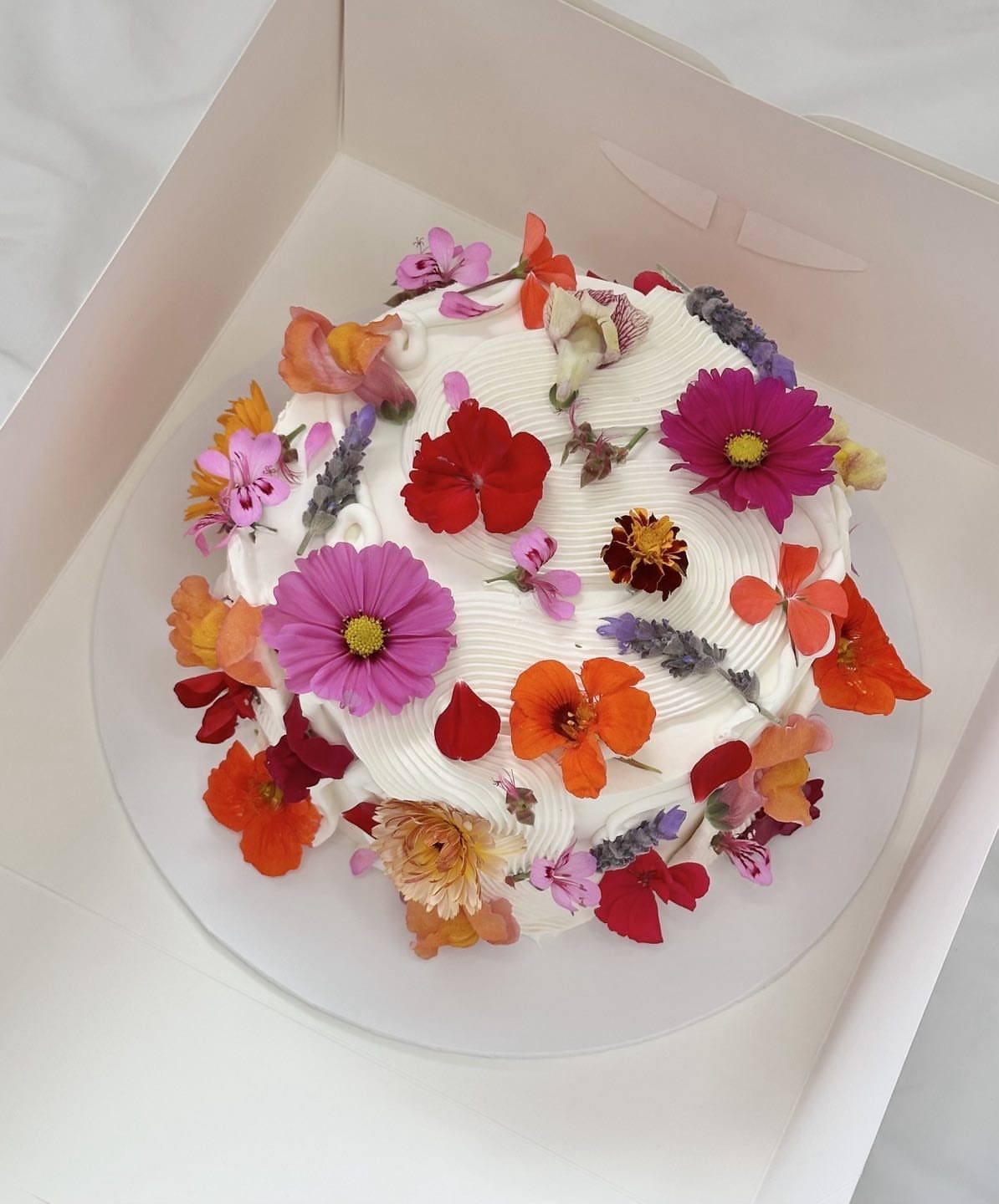21 Cake Decoration Ideas for Every Skill Level 10 White frosted cake decorated with colorful edible flowers in a white box