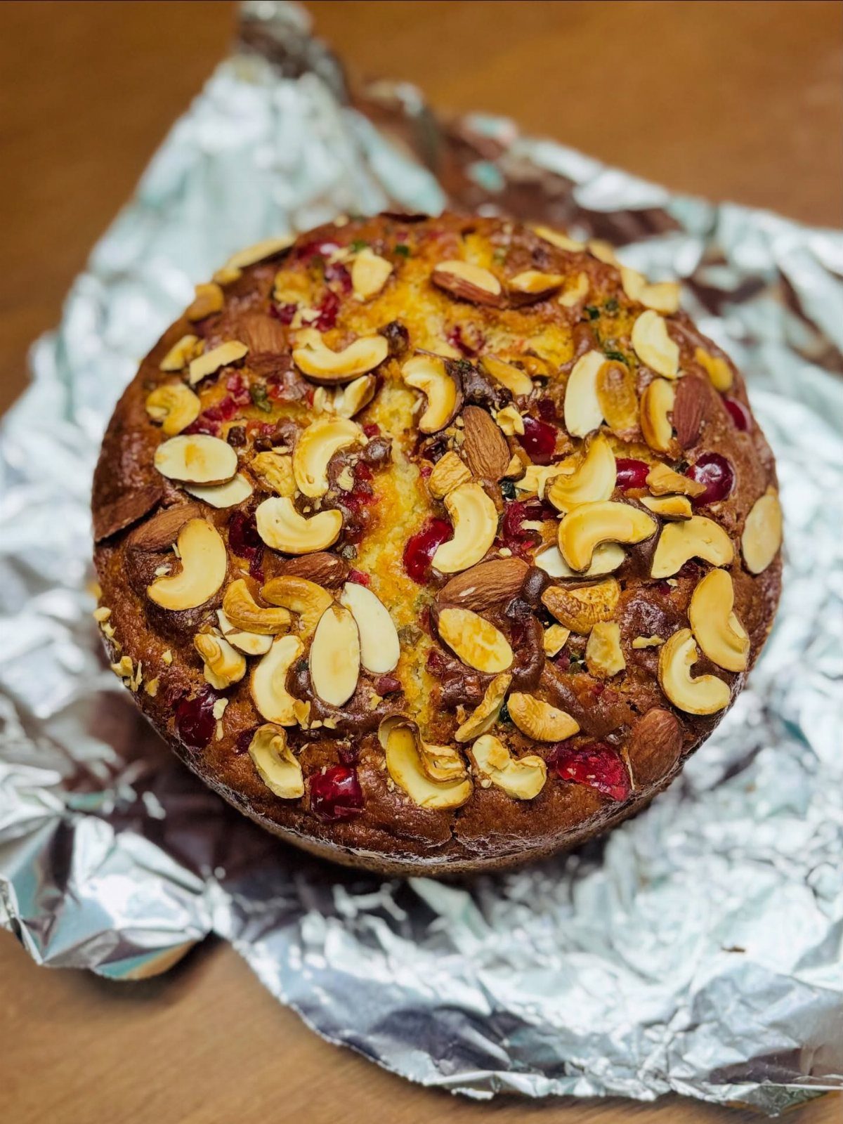 21 Cake Decoration Ideas for Every Skill Level 14 Round golden cake topped with cashews, almonds, and red candied cherries on foil.