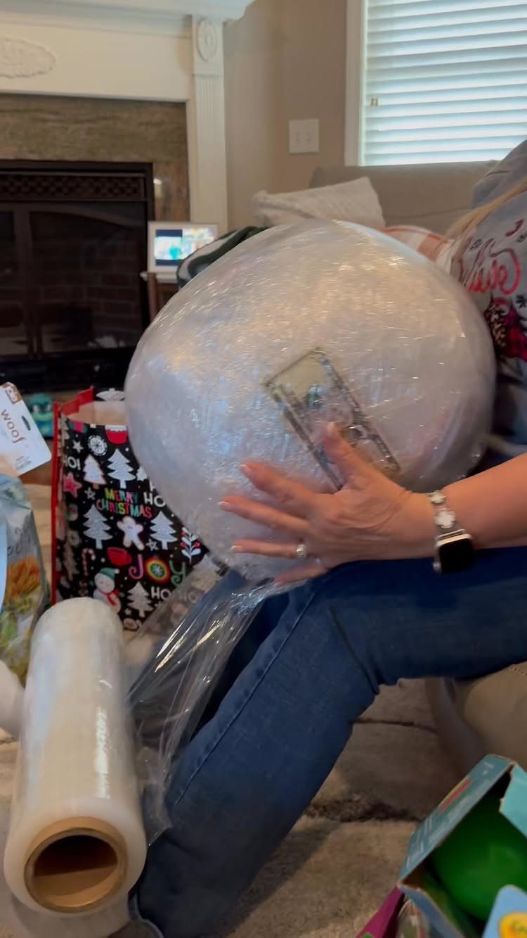 Person holding a large plastic wrap ball with a dollar bill inside.