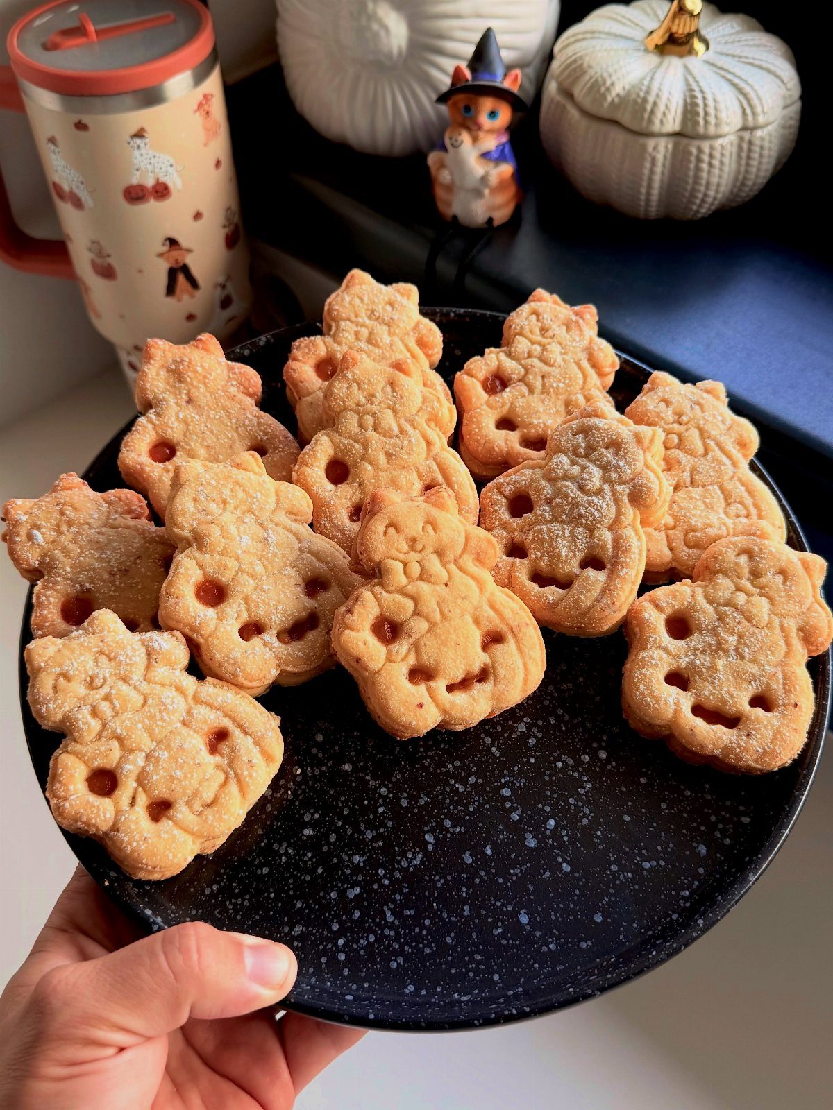 21 Pumpkin Theme Food Ideas for Fall Gatherings 7 Pumpkin-shaped sandwich cookies with orange filling on a black speckled plate.