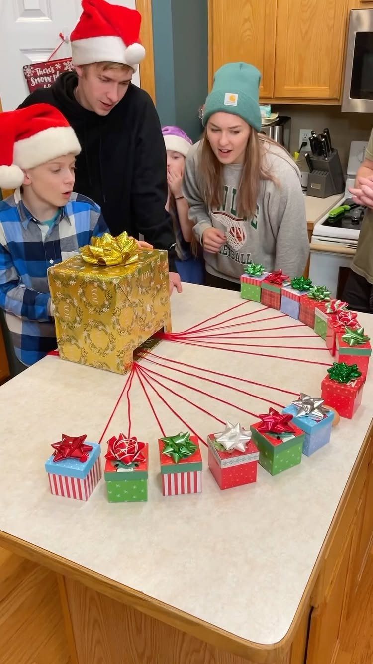 People gathered around a large gold gift connected by red strings to smaller presents.