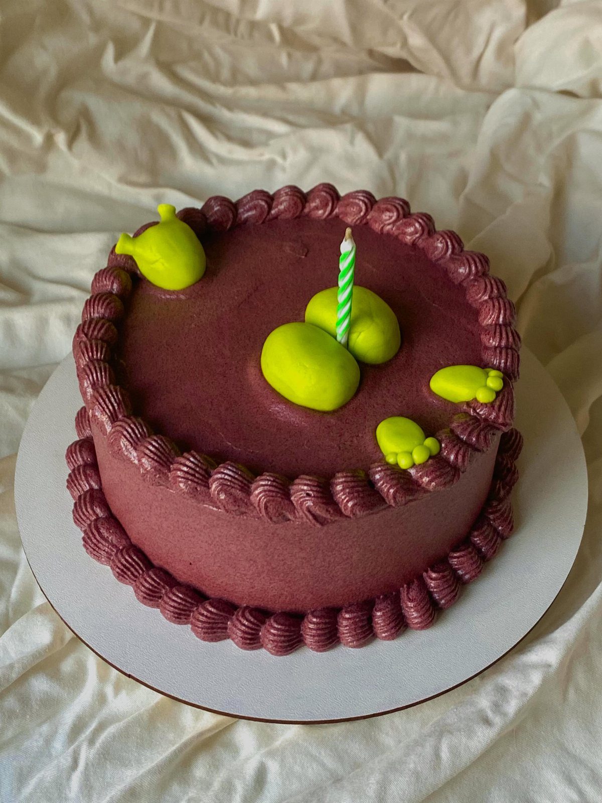 19 Funny Cake Designs That Steal the Whole Party 10 Maroon cake with a lime green fondant person sinking into the top surface.