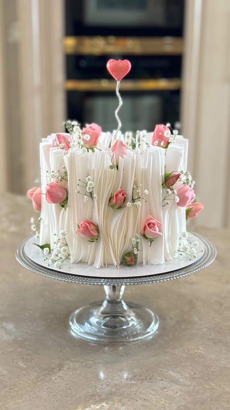 21 Cake Decoration Ideas for Every Skill Level 19 White frosted cake with pink roses and white chocolate shards on glass stand